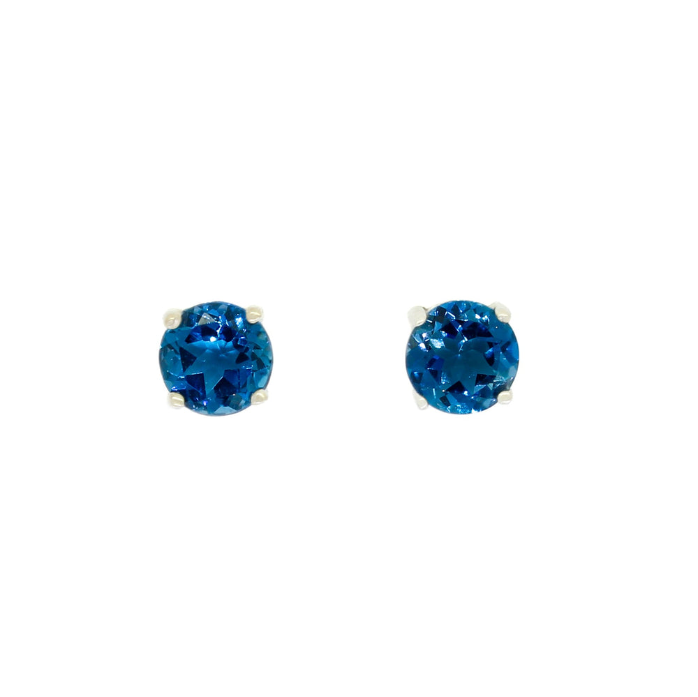 A product photo of two silver stud earrings sitting on a white background. Held in place by 4 silver claws each are two dazzling round-cut london blue topaz stones, reflecting shades of ocean-blue light from their many edges.