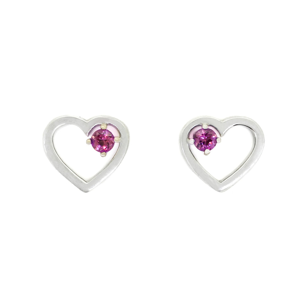 
            
                Load image into Gallery viewer, A product photo of two silver heart-shaped stud earrings sitting on a white background. A delicate, 2.5mm round warm purple rhodalite stone is nestled in the top right corner of each heart-shaped frame.
            
        