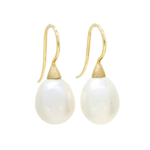 A product photo of a simple pair of yellow gold shepherd's hook earrings suspending two large white pearls over a white background. The pearls are attached to the hooks by small, thick cones of gold.