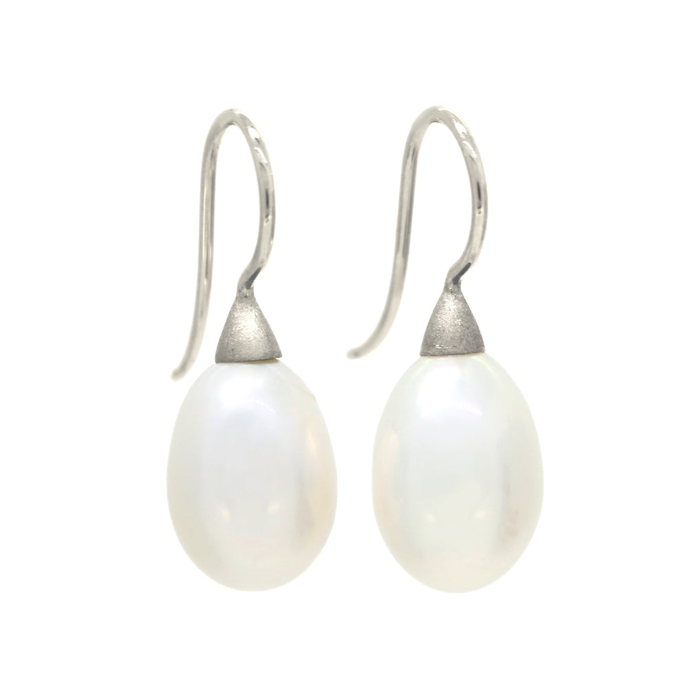 A product photo of a simple pair of white gold shepherd's hook earrings suspending two large white pearls over a white background. The pearls are attached to the hooks by small, thick cones of gold.