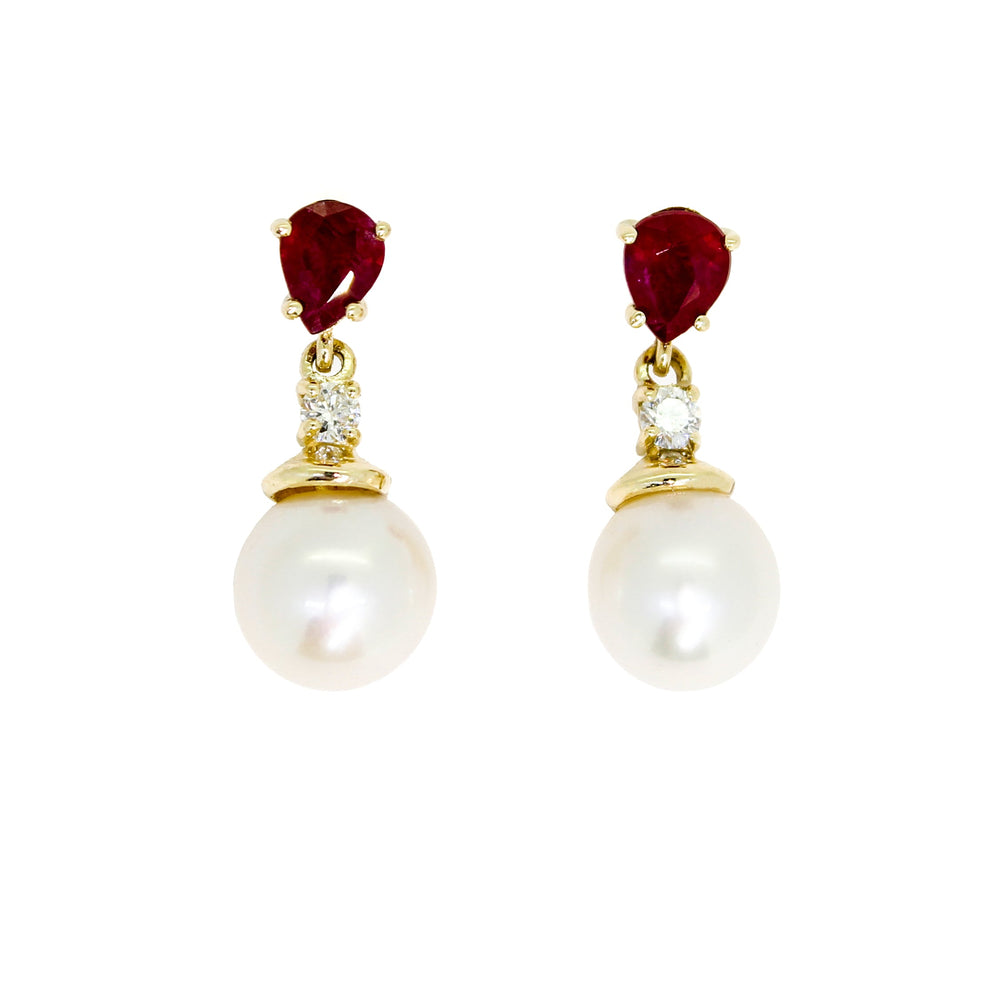 A product photo of a pair of ornate pearl drop stud earrings in yellow gold suspended over a white background. The pearls are creamy white and round, with one small diamond followed by a pear-shaped ruby on each piece linking them to the back of the golden stud.