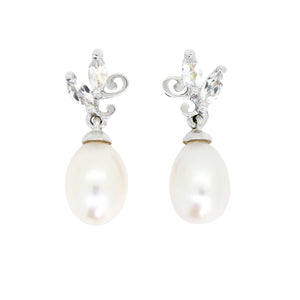 A product photo of a pair of ornate pearl drop stud earrings in white gold suspended over a white background. The large pearls are creamy white and teardrop-shaped, with two small marquise-cut silver topaz stones and subtle filigree detailing on each piece linking them to the back of the golden stud.