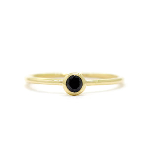 
            
                Load image into Gallery viewer, A product photo of a delicate yellow gold stacking ring with a tiny, bezel-set black diamond in the centre sitting on a white background. The band is slim and thread-like, with the focus drawn to the petite 3mm glinting black centre stone.
            
        