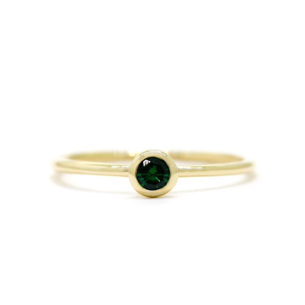 
            
                Load image into Gallery viewer, A product photo of a delicate yellow gold stacking ring with a tiny, bezel-set tsavorite in the centre sitting on a white background. The band is slim and thread-like, with the focus drawn to the petite 3mm glinting green centre stone.
            
        