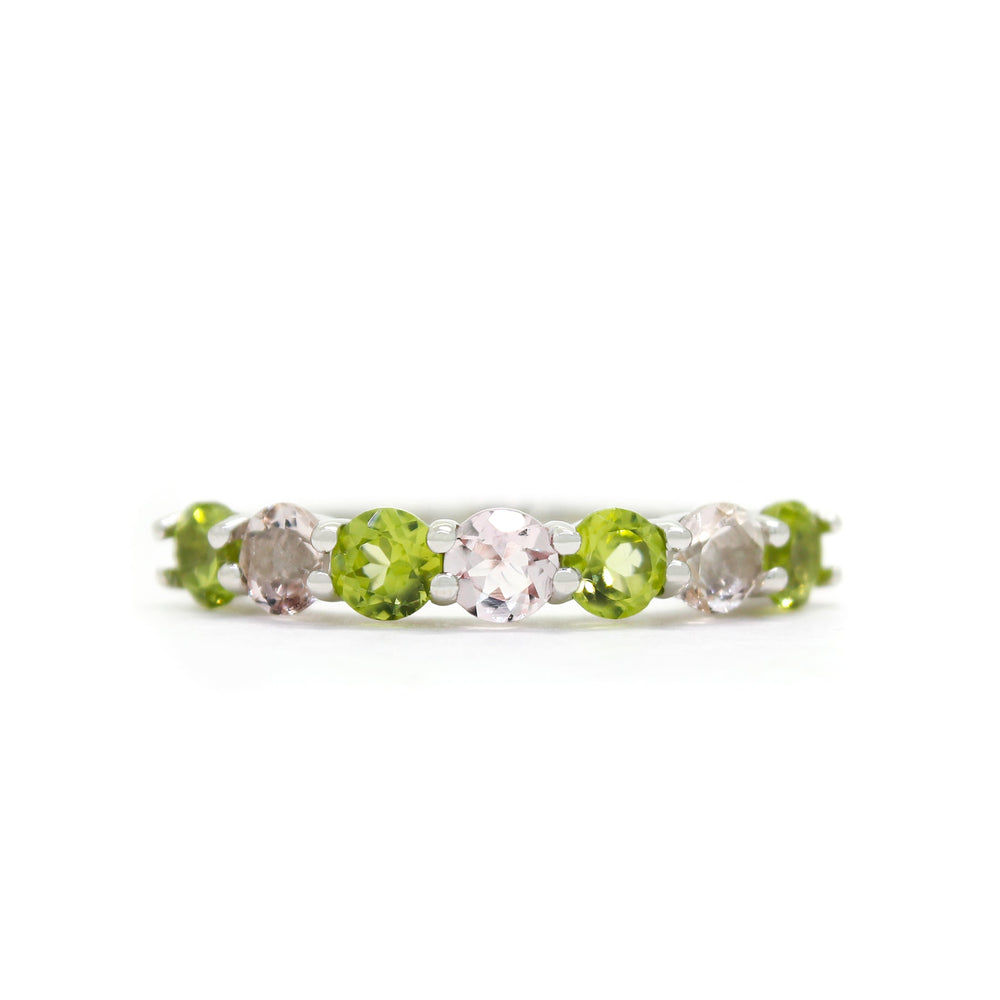 A product photo of a bold, alternating-gemstone ring in 9k white gold – made up of 7 3.5mm peridot and pink morganite stones – sitting on a white background.