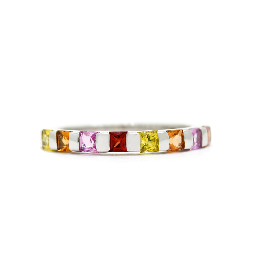 A product photo of a bold, multi-gemstone stacking ring in 9k white gold – made up of multi-coloured sapphire jewels – sitting on a white background.