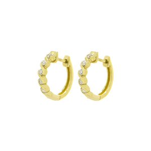 A product photo of two diamond huggies hoop earrings set in solid 9ct yellow gold suspended against a white background. The diamonds are set in looping waves of golden detailing, with each "wave" curling gently around a single white diamond to a total of 5.