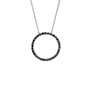 A product photo of a solid 9ct white gold and black diamond pendant suspended by a golden chain against a white background. The design is made up of 30 black diamond jewels arranged in a perfect hollow circle, reminiscent of an abstract ouroboros jewellery design. All of the diamonds are held in place by delicate golden claws.