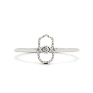 A product photo of a delicate diamond ring set in solid 9ct white gold sitting on a white background. At the front of the ring is a minimalistic Hamsa hand design (also known as the Hand of Fatima and The Hand of Miriam) made up of slim filigree detailing, with an oval frame of gold holding a single white diamond in place, almost mimicking the shape of an eye.