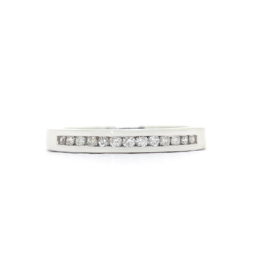 A product photo of a bold, minimalistic half-eternity diamond ring made of solid 9ct white gold. 13 bright white diamonds are embedded along the centre of the band, framed at the top and bottom by solid, squared golden strips.