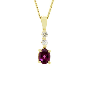 A product photo of a 9k yellow gold diamond and rhodalite garnet pendant supended by a chain against a white background. The pendant is slim and delicate, consisting of 2 0.04ct round white diamonds linked together by golden claw settings, ending off with a gorgeous, oval-shaped plum rhodalite jewel as the main attraction.