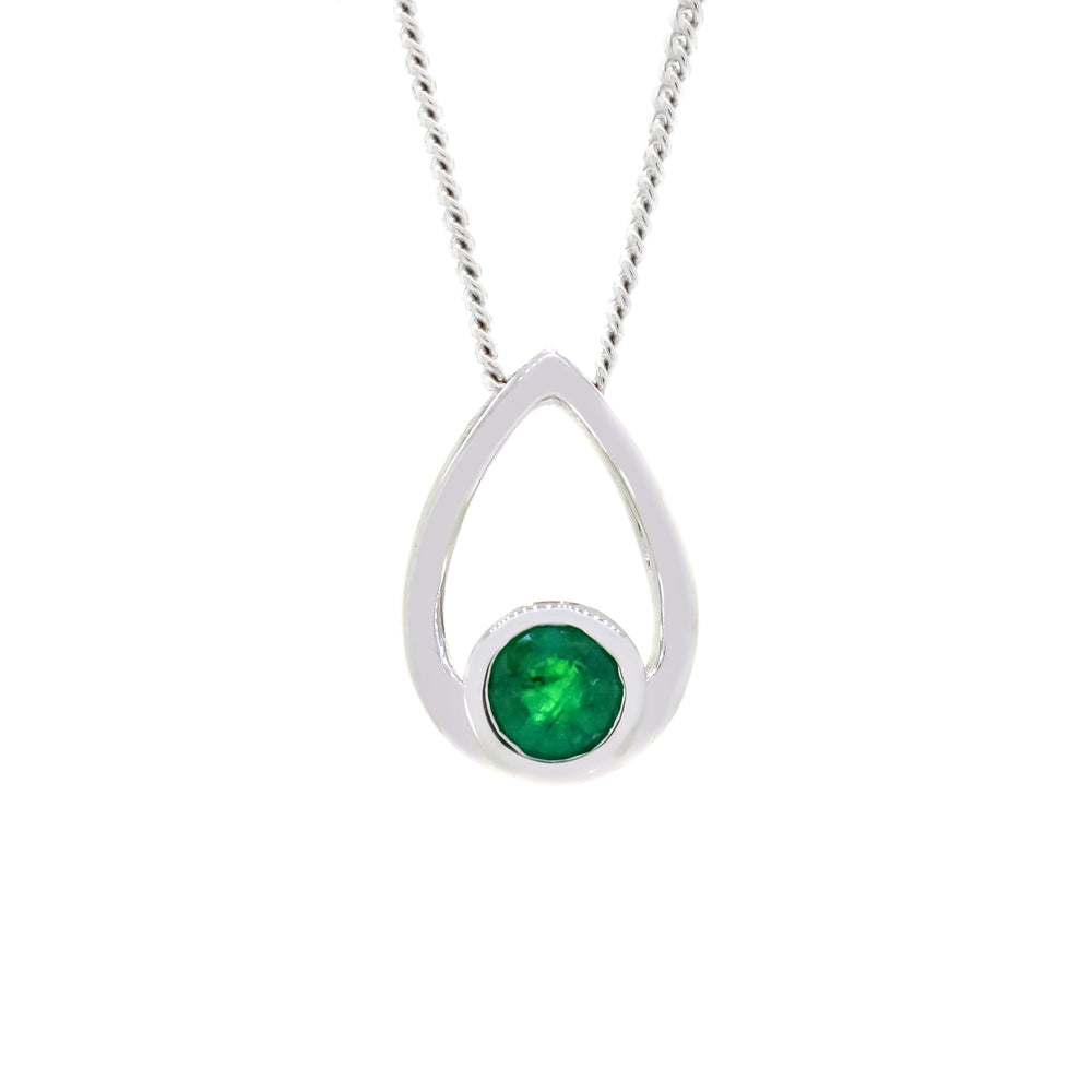 
            
                Load image into Gallery viewer, A product photo of a white gold pendant with a single, tiny emerald stone encased in white gold suspended against a white background. The bezel-set emerald sits at the bottom of a golden frame, shaped like a teardrop.
            
        
