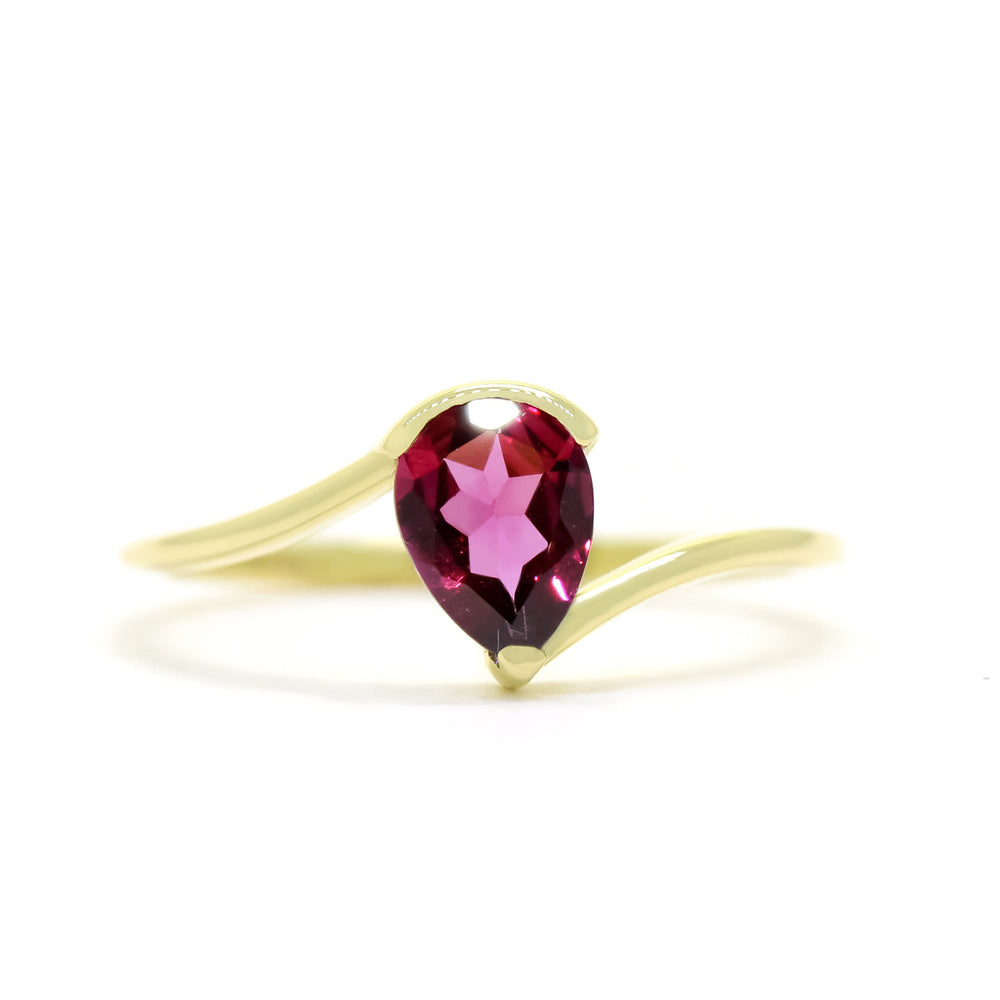 
            
                Load image into Gallery viewer, A product photo of a yellow gold rhodalite ring sitting against a white background. The gold band is plain and smooth, and curves to meet at the top and bottom of a large, 7x5mm pear shaped rhodalite centre stone - holding it in place.
            
        