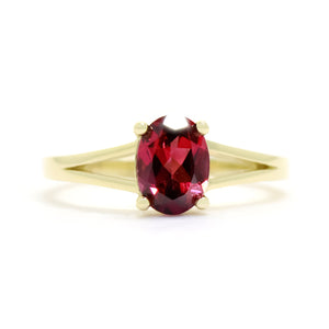 
            
                Load image into Gallery viewer, A product photo of a yellow gold split band rhodalite ring sitting on a white background. The ring is simple, yet sophisticated in its elegance - splitting halfway along the band&amp;#39;s length into two golden prongs that meet on either side of the deep, warm purple centre jewel.
            
        