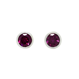 A product photo of white gold grape garnet earrings sitting on a white background. The round stones are encased in a thick layer of white gold bezel framing. The grape garnet purple-coloured gemstones reflect warm pink and purple light from their many edges.