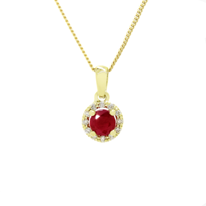 A product photo of a 0.82ct Round Ruby Pendant with a Diamond Halo in 9k Yellow Gold suspended against a white background. The circle-cut ruby stone is surrounded by a thick frame of ornately detailed yellow gold and diamond detailing. It is suspended by a simple gold chain. The stone is a deep pinky red, reflecting sanguine and magenta hues across its multi-faceted edges.