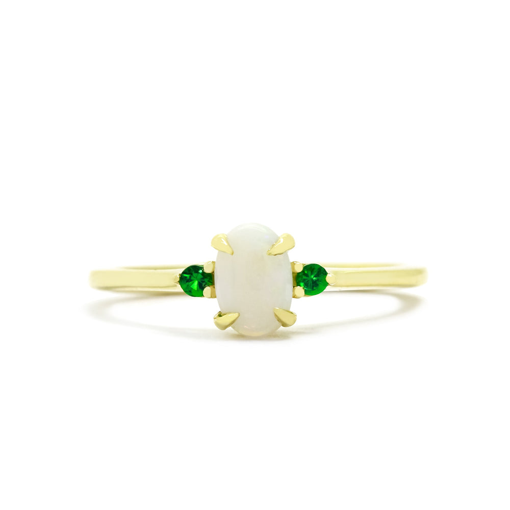 A product photo of a delicate 9ct yellow gold 6x4mm white opal and tsavorite trio ring sitting on a white background. The fiery opalite centre stone is hugged on either side by a bright green tsavorite jewel.
