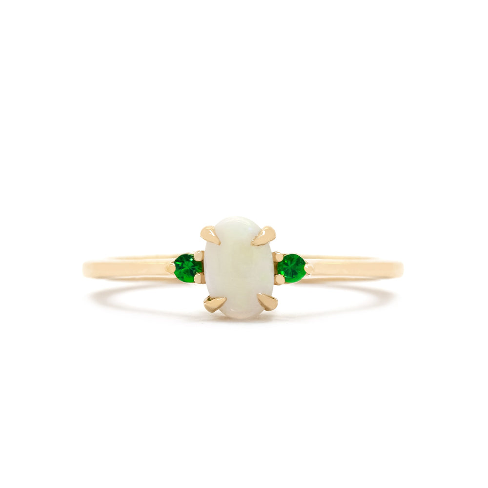 A product photo of a delicate 9ct rose gold 6x4mm white opal and tsavorite trio ring sitting on a white background. The fiery opalite centre stone is hugged on either side by a bright green tsavorite jewel.