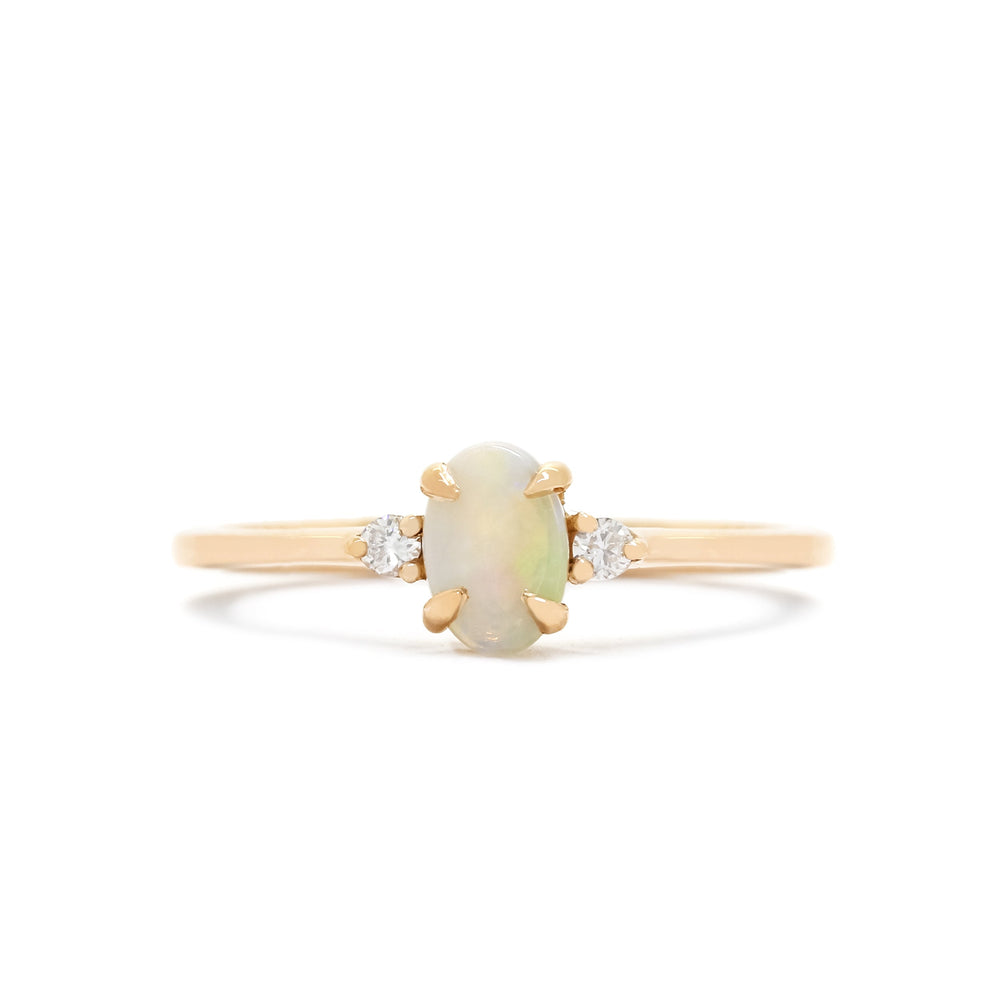A product photo of a delicate 9ct rose gold 6x4mm white opal and diamond trio ring sitting on a white background. The fiery opalite centre stone is hugged on either side by a bright white diamond jewel.