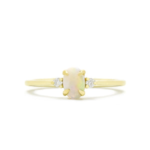 A product photo of a delicate 9ct yellow gold 6x4mm white opal and diamond trio ring sitting on a white background. The fiery opalite centre stone is hugged on either side by a bright white diamond jewel.