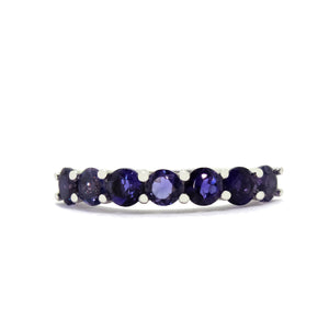 
            
                Load image into Gallery viewer, A product photo of a deep, dark blue eternity ring in solid 9 karat white gold – made up of 7 3.5mm iolite gemstones – sitting on a white background. The iolites are a deep and dark blue, and could be an affordable alternative to a sapphire eternity ring.
            
        