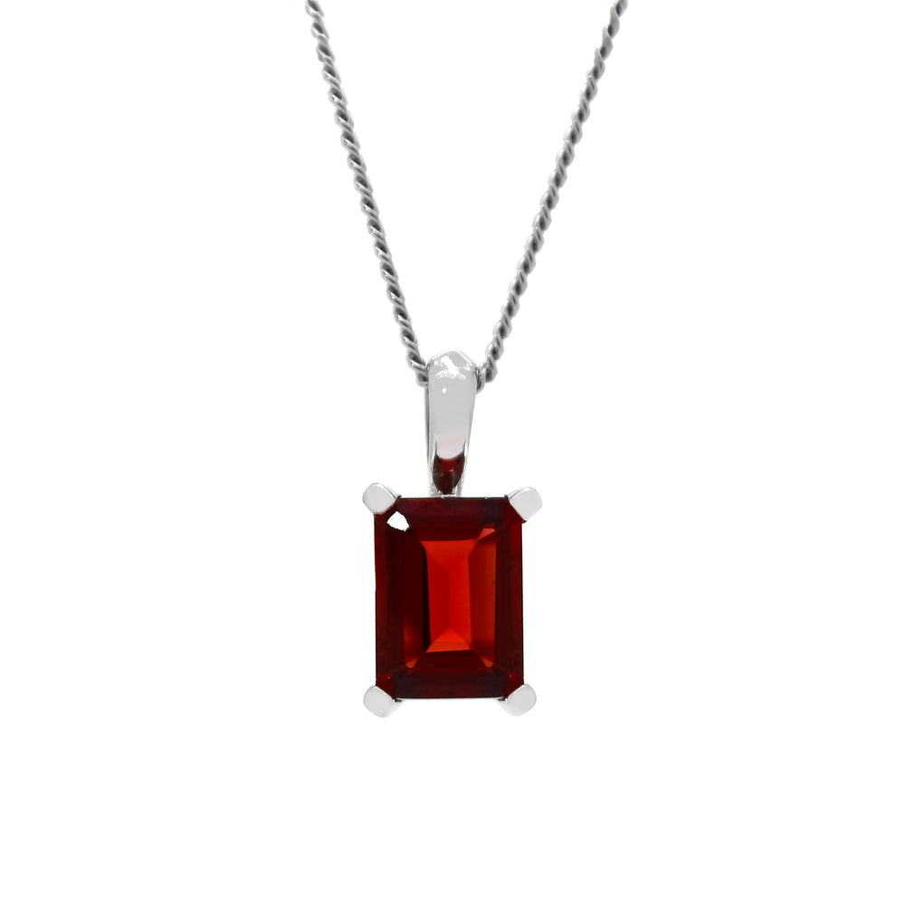 A product photo of a Rectangular Garnet Pendant in 9k Yellow Gold suspended against a white background. The impressively large and deeply-coloured stone is contrasted by its overall minimalistic design, 4 simple golden claws holding the gem in place. It is suspended by a simple gold chain. The stone is a deep red, reflecting sanguine hues across its multi-faceted edges.