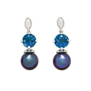 This product image features a pair of solid white gold gemstone and pearl earrings with a unique design. The main components are two deep blue round-cut london blue topaz jewels, each one set above a single, rounded dark blue peacock pearl