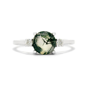 
            
                Load image into Gallery viewer, A product photo of a white gold moss agate and diamond trio ring sitting on a white background. The large and round, naturally-included moss agate gemstone stands in stark contrast to the classic look of the single 0.05ct white diamonds on either side. The moss agate stone is unusually bright and translucent - a semi-opaque white with stunning deep green tendrils of swirling dendritic inclusions, appearing like moss within clear water.
            
        