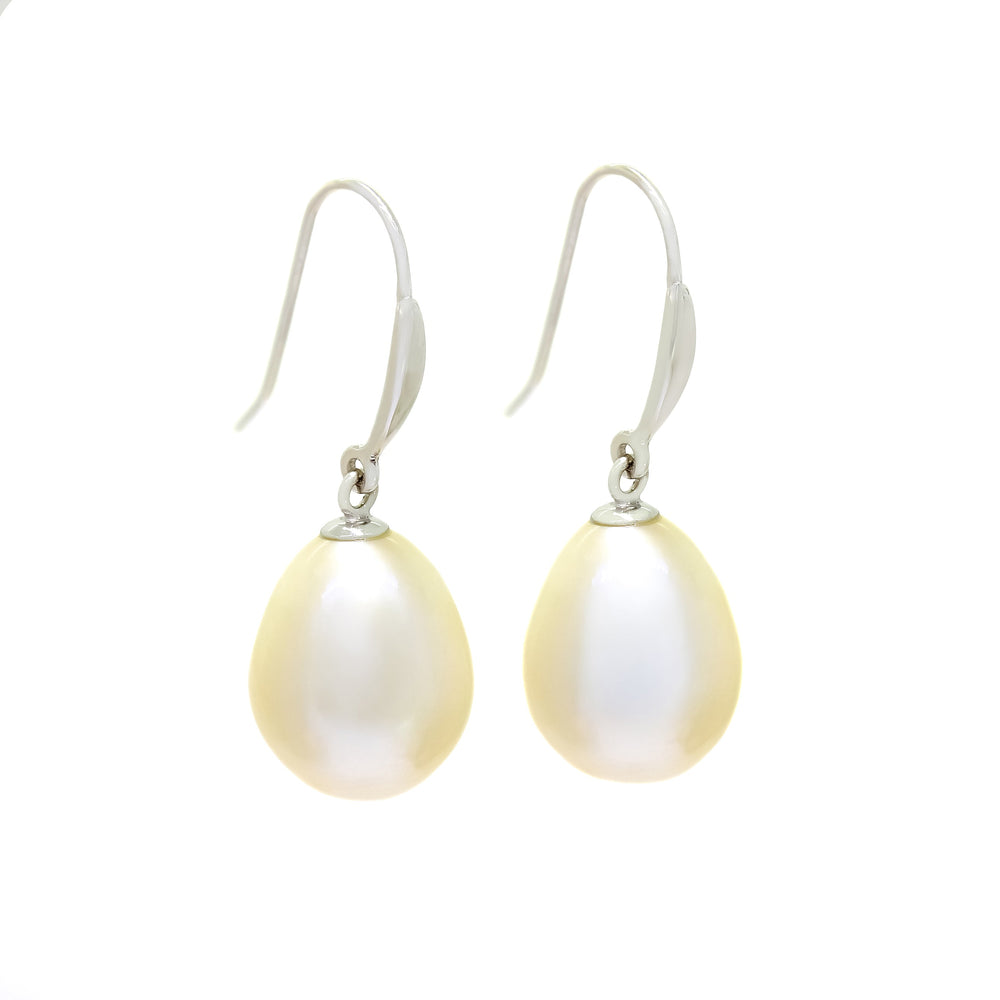 This product image shows a pair of white pearl drop earrings. The earrings are made up of two white egg-shaped pearl stones set with solid white gold shepherd’s hooks.