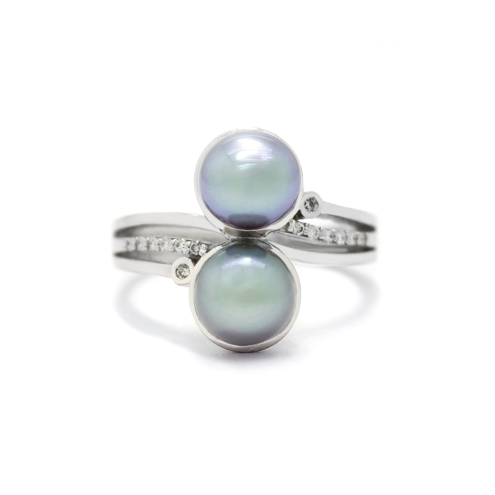 
            
                Load image into Gallery viewer, This product image shows a unique pearl and diamond ring in 9 karat white gold. The band consists of three prongs extending towards the steel grey pearls in the centre of the design, stacked on top of one another. The middle prong on either side is embedded with diamonds, while the outer prongs on the top and bottom feature a small white diamond in a bezel-setting on its end.
            
        