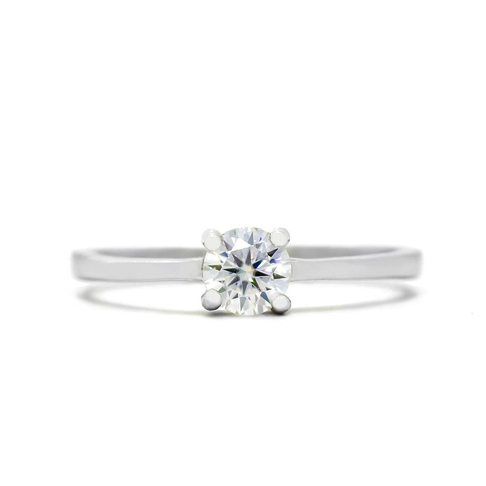 
            
                Load image into Gallery viewer, A product photo of a moissanite solitaire ring in 925 sterling silver sitting on a clear white background. A single reflective moissanite gem sits in the centre of the smooth silver band, held securely in place by 4 delicate claws.
            
        
