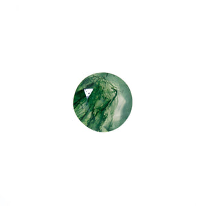 A product image of a loose 7mm faceted round-cut moss agate stone. The stone has a cool white milky colour, with deep, swirling green natural inclusions - appearing as moss-like structures or delicate inkspills within the stone. The faceted edges reflect bright white light.