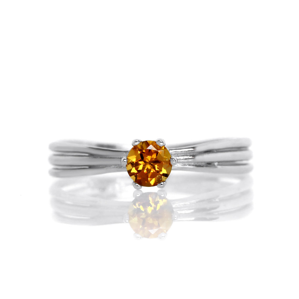 A product photo of a simple silver solitaire ring with a unique band detail and a 4mm round citrine centre stone sitting on a white background. The band is styled to appear as 3 little silver bands, tilted slightly outwards and "overlapping" towards the back of the ring.