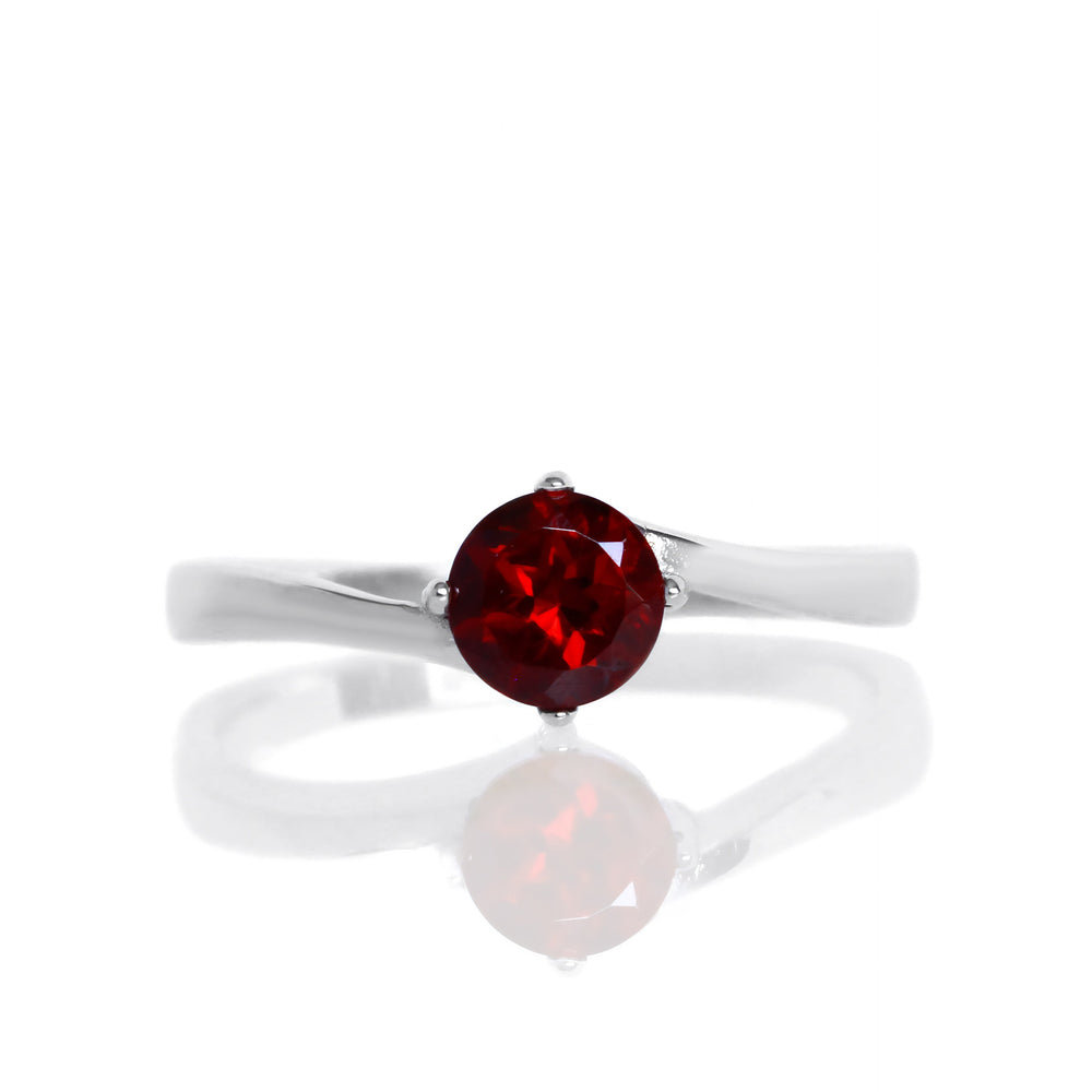 A product photo of a curved-band silver solitaire ring with a crimson red garnet centre stone sitting on a white background. The deep red gemstone colour would be a good ruby alternative.