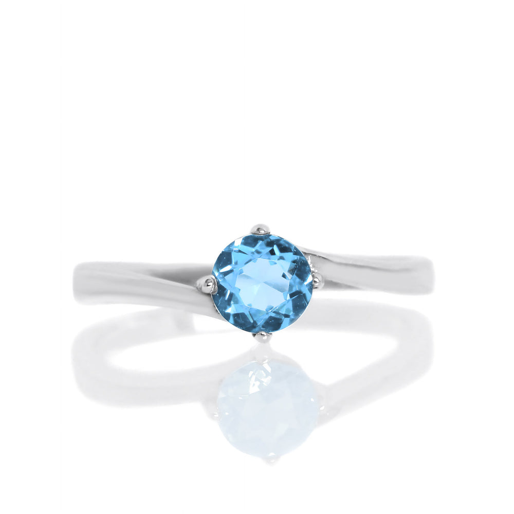A product photo of a curved-band silver solitaire ring with a bright bllue Blue Topaz centre stone sitting on a white background.