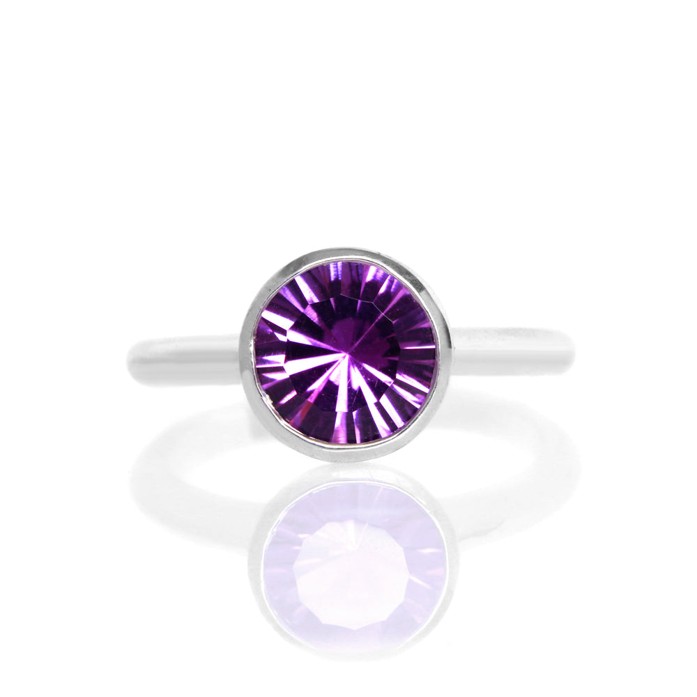 
            
                Load image into Gallery viewer, A product photo of a silver ring with a bezel-set amethyst centre stone sitting on a white background. The silver band is simple and smooth, connecting on either side of a large, statement-sized garnet stone surrounded by a solid frame of silver.
            
        
