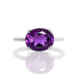 
            
                Load image into Gallery viewer, A product photo of a silver ring with an impressive oval amethyst centre stone sitting on a white background. The band is simple and rounded, with a single 10x8mm amethyst centre stone, held in place with 8 delicate silver claws, each split into pairs of 2.
            
        