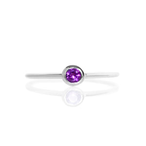 
            
                Load image into Gallery viewer, A product photo of a delicate silver stacking ring with a tiny, bezel-set amethyst in the centre sitting on a white background. The band is slim and thread-like, with the focus drawn to the petite 3mm glinting purple centre stone.
            
        