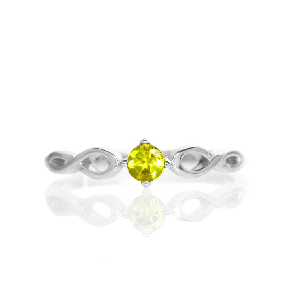 A product photo of an ornate silver ring with a yellow tourmaline centre stone sitting on a white background. The silver band splits halfway along its length, becoming twisting and serpentine in appearance before meeting on either side of the dazzling yellow 3.5mm stone, which is held in place by 4 silver claws.