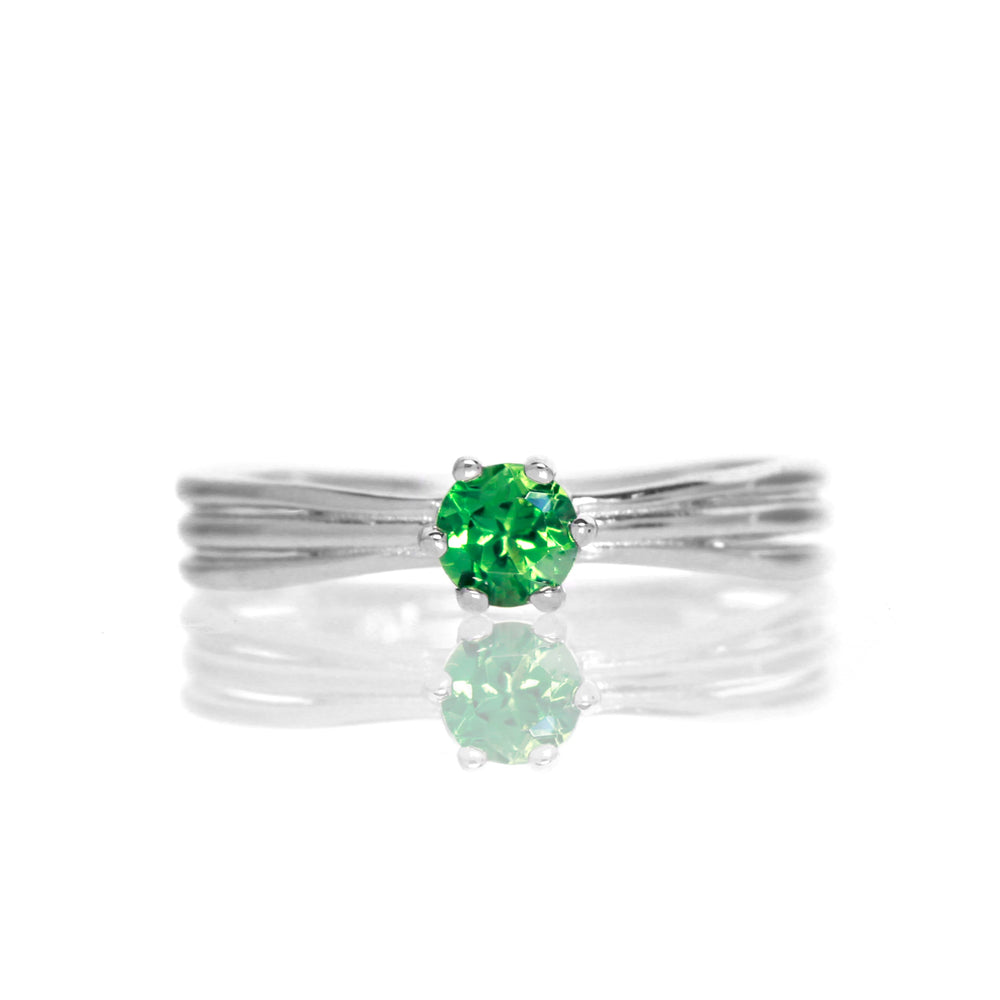 
            
                Load image into Gallery viewer, A product photo of a simple silver solitaire ring with a unique band detail and a 4mm round green tourmaline centre stone sitting on a white background. The band is styled to appear as 3 little silver bands, tilted slightly outwards and &amp;quot;overlapping&amp;quot; towards the back of the ring.
            
        