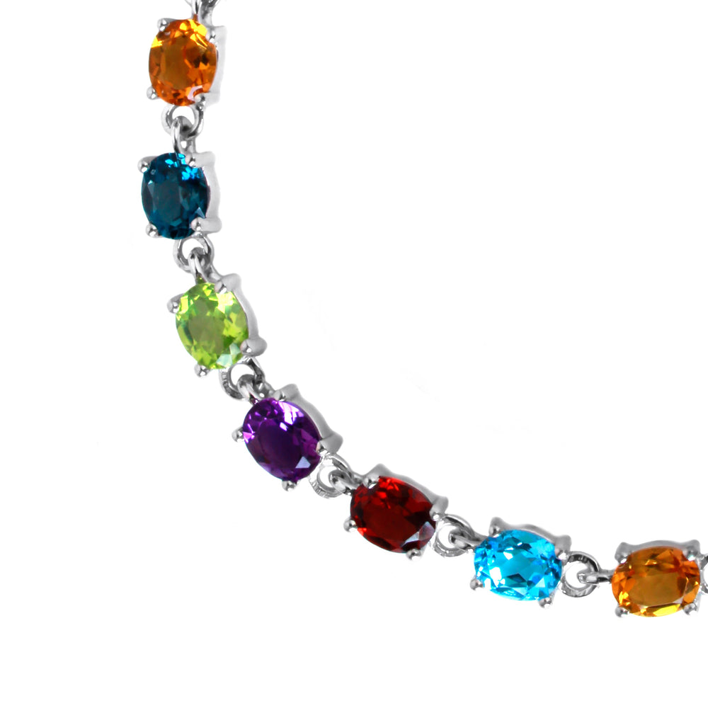 A product photo of a silver bracelet featuring 21 6x4mm oval multi-coloured gemstones, strung along in the following order: blue topaz, garnet, amethyst, peridot, london blue topaz and citrine, before repeating until 21.