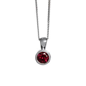 A product photo of a round rhodalite pendant in a silver bezel setting hanging by a chain over a white background.