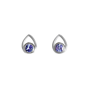 A product photo of a pair of tanzanite earrings in solid 925 sterling silver sitting on a clear white background. The earrings are in the shape of a small teardrop, with a petite, silver-encased tanzanite gem nestled at the base of each one. The silver teardrop shape is smooth and unblemished.