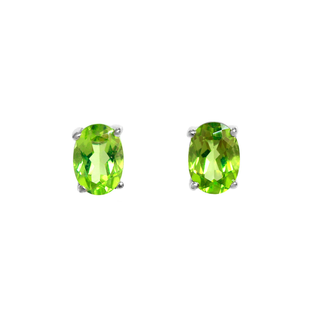A product photo of 7x5mm Oval Shaped Peridot Earring Studs in solid sterling silver sitting on a plain white background. The 2 peridot stones measure 5mm across and are a bright grassy green, reflect chartreuse hues across their multi-faceted edges, and are each held in place by dainty silver claws.