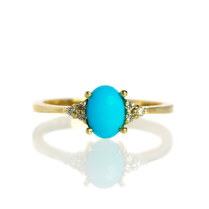 
            
                Load image into Gallery viewer, A product photo of a yellow gold ring with trio diamond detailing and a cabochon cut Sleeping Beauty turquoise centre stone. The band is simple and smooth. The 7x5mm turquoise stone is perfectly opaque and unblemished, and is hugged on either side by 3 dazzling 0.01ct white diamonds each - to a total of 6.
            
        