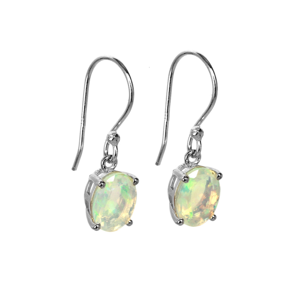 A product photo of a pair of sterling silver rainbow opal drop earrings suspended against a white background. The drop earrings feature shepherd hooks, and the 9x7mm oval-shaped faceted opals are held in place by 4 delicate silver claws.