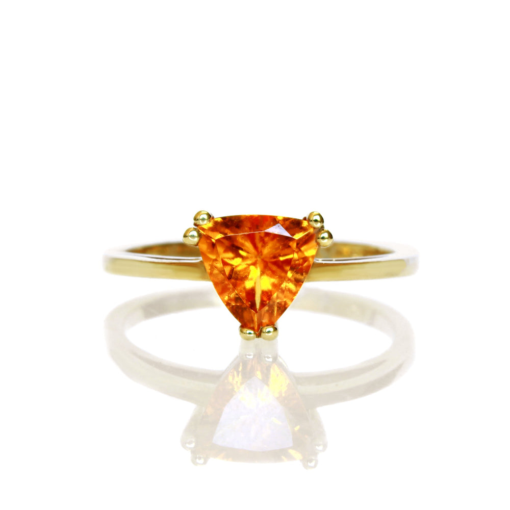 A product photo of an orange mandarin garnet solitaire ring in solid 9 karat yellow gold on a white background. The ring is composed of a simple rounded gold band and a 7mm bright orange trilliant garnet stone in the cente.