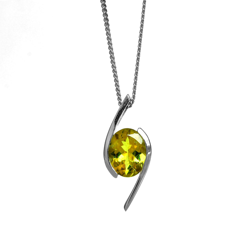 A product photo of a yellow tourmaline pendant in solid 9 karat white gold suspended by a gold chain over a plain white background. The large, pale yellow tourmaline stone is held in place by stylish, minimalistic sweeps of white gold, one on either side.