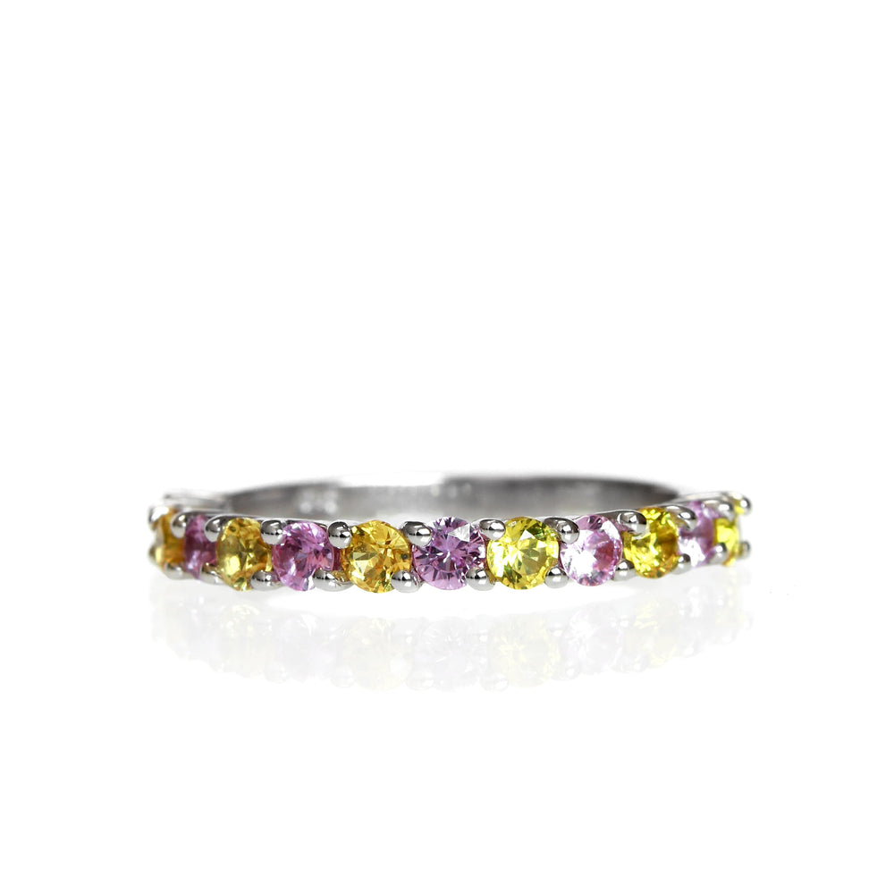 A product photo of a white gold eternity band with 13 pink and yellow sapphire gemstones in alternating order embedded along its length on a white background.