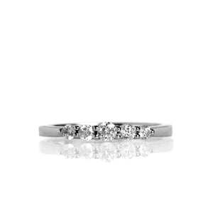 A product photo of a delicate, dazzling diamond eternity ring set in 9ct white gold. The ring is made up of 5 bright white diamonds set in a slim golden band, with the largest diamond set directly in the middle.